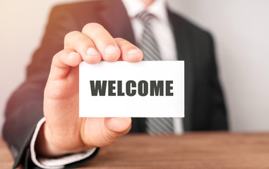 Businessman holding a card with text WELCOME