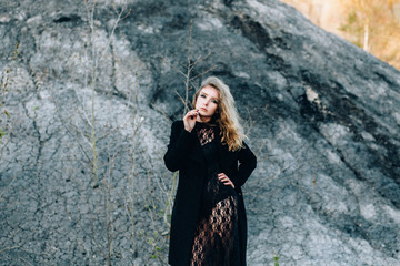 Portrait of a sexy young woman in a black dress with a bright evening make-up on the background of a lifeless desert.