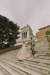 Bride and groom walking outdoors at Spagna Square and Trinita' dei Monti in Rome, Italy