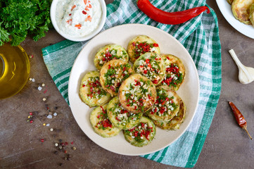 Fried circles of young zucchini with garlic, red pepper, greens on a plate. Vegetarian menu. Top view.