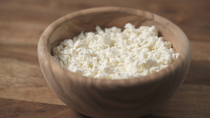 closeup crumbly cottage cheese in wood bowl