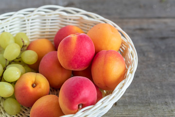 Delicious ripe apricots in a basket on wooden background.