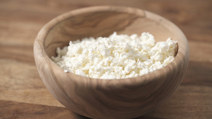 closeup crumbly cottage cheese in wood bowl