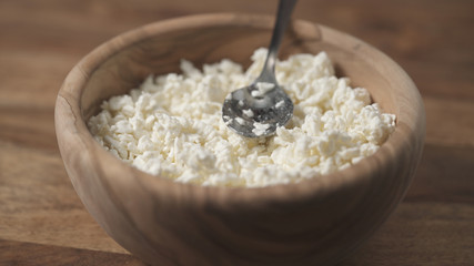 closeup crumbly cottage cheese in wood bowl