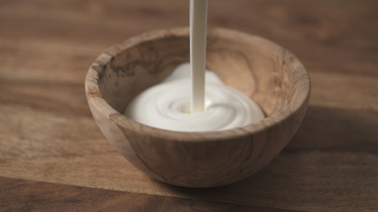 sour cream pour into wood bowl closeup