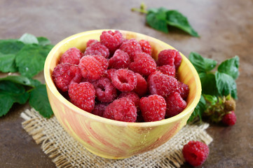 Fresh ripe tasty raspberries in a yellow ceramic bowl. Summer berries.
