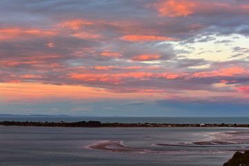 Orange red clouds caused by the setting sun at Avon Heathcote Estuary in Christchurch, New Zealand