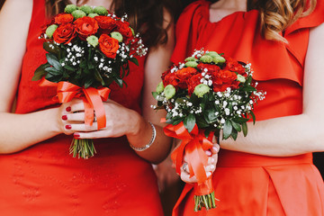 Bridesmaids in red dresses and bouquets, closeup