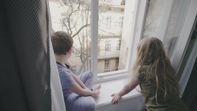 Two young children watching through a window