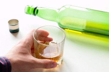 alcoholic holding a glass with alcohol on an empty bottle background
