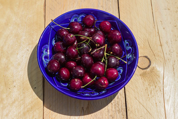 blue plate of ripe sweet cherry on  wooden table