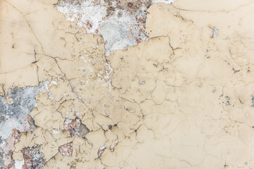 Old white paint exfoliates with cracked layers on the wall of concrete.