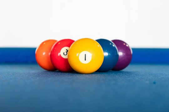 diamond shape of 9-ball pool balls placed in rack position on blue felt table, focus on number one, close up
