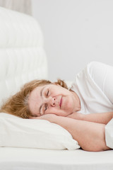Obraz na płótnie Canvas senior woman sleeping on bed at home. Space for text