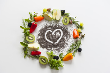 wreath of vegetables and fruits with heart from chia seeds on white background