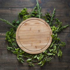 Empty round wooden cutting board. Various sweet basil herb leaves edged.. Healthy food concept. Top view with copy space.