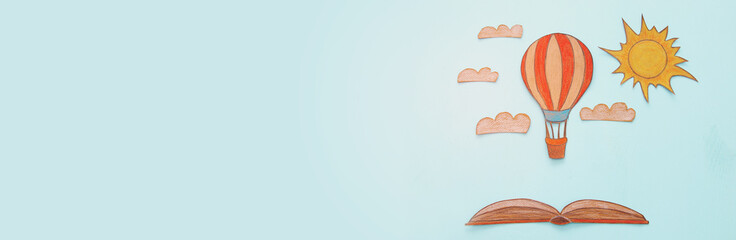 Banner of Hot air balloon, space elements shapes cut from paper and painted over wooden blue background.
