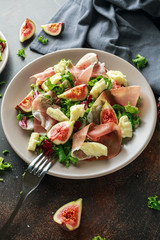 Fresh figs salad with prosciutto, green mix and cheese in a plate