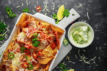Maxican-style tortilla nachos chips topped with tomato salsa, sliced chilies and melted cheese...