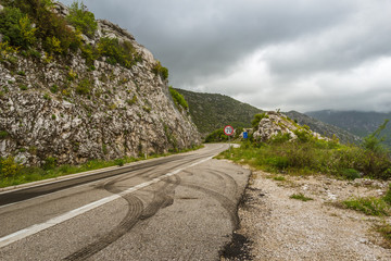 Curved Mountain road with street sign and skid marks taken in Montenegro