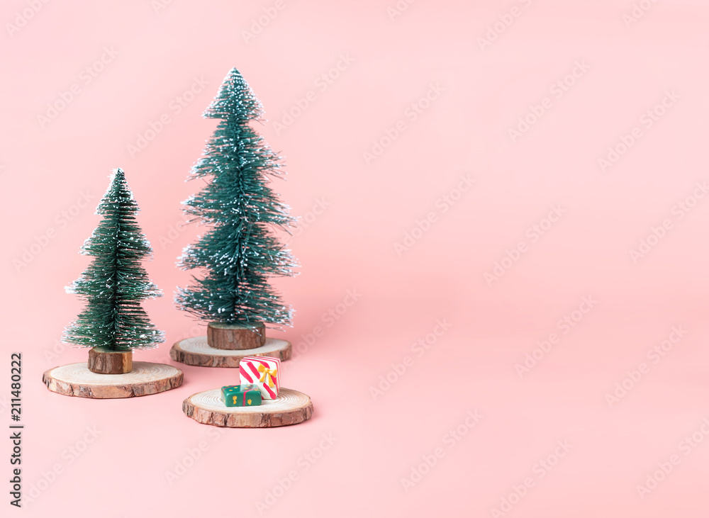 Poster tree christmas tree on wood log slice with present box on pastel pink studio background.holiday fest