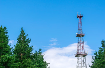 telecommunication tower with a parabolic antennas on a background of blue sky and clouds