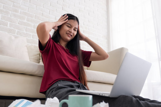 Asian woman freelancer stress emotion while working with laptop and paperwork at sofa in living room in house.work at home concept.