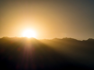 silhouette image - sunlight behind the mountain at sunrise