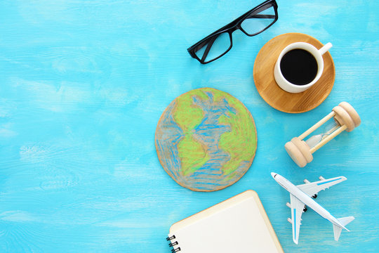 top view image of airplane , earth globe and coffee over blue wooden background.