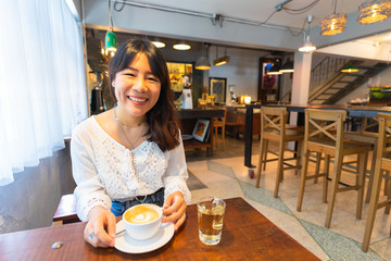 Young Asian woman enjoying coffee in cafe.