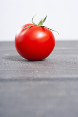 one tomato on old black wood table