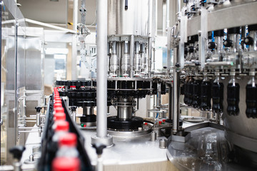 Obraz premium Bottling factory - Black juice bottling line for processing and bottling juice into bottles. Selective focus.