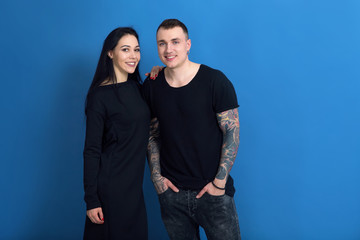 Couple in love, woman and man with tattoos together on the blue background.