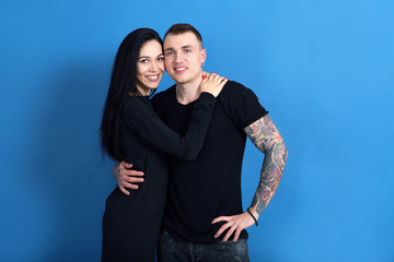 Couple in love, woman and man with tattoos together on the blue background.