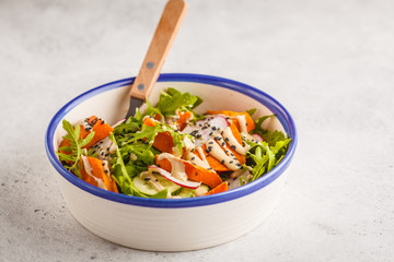 Bright vegan salad with arugula, sweet potato, radish, tahini dressing and cucumber, white background, copy space. Healthy vegan food concept.