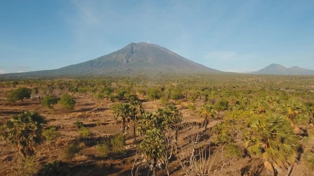 Aerial view of Volcano Mount Agung with smoke at sunrise, Bali, Indonesia. Conical volcano of Gunung Agung. Rural mountain landscape. 4K, Aerial footage.