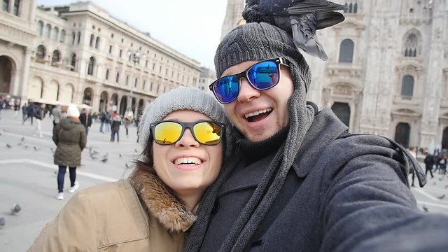Happy tourists taking a self portrait with phone in front of Duomo cathedral,Milan. Winter tourism concept