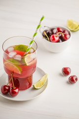 Cherry juice with ice and lime in a glass beaker, light background. White background.