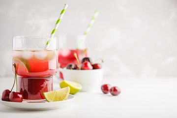 Cherry juice with ice and lime in a glass beaker, light background. White background.