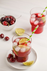 Cherry juice with ice and lime in a glass beaker, light background. White background.