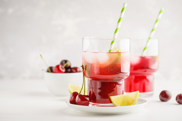 Cherry juice with ice and lime in a glass beaker, light background. White background.