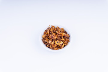 Deep fried shallots crisp / fried crispy onion flakes  (bawang goreng) in white bowl over wooden background.