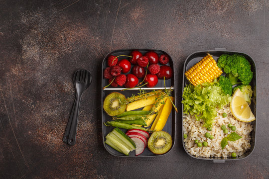 Healthy vegan meal prep containers with brown rice, broccoli, vegetables, fruits and berries overhead shot