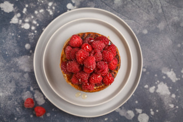 Homemade pancakes with raspberries on a gray plate, dark background, top view. Healthy vegan food concept.