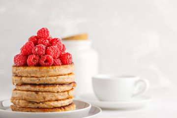 Vegan pancakes with raspberries and chia seeds on white plate, white background. Healthy vegan food concept.