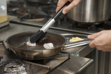 The hands of the cook, grilling shrimp
