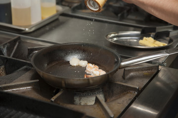 The hands of the cook, grilling shrimp