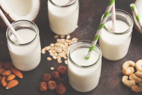 Vegan alternative nut milk in glass bottles on dark background. Healthy vegan food concept.