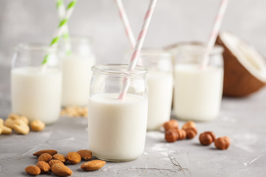 Vegan alternative nut milk in glass bottles on gray background. Healthy vegan food concept.