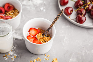 Homemade granola with yogurt and berries in small white bowls. Healthy food concept.